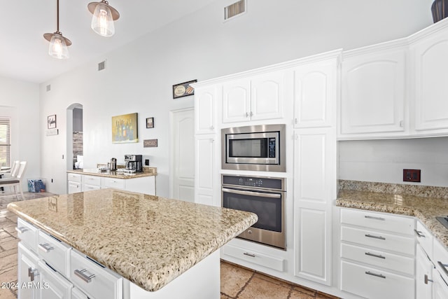 2731 W Desert Ranch Rd, Phoenix, AZ 85086 - kitchen featuring appliances with stainless steel finishes, arched walkways, a center island, light stone counters, and white cabinets