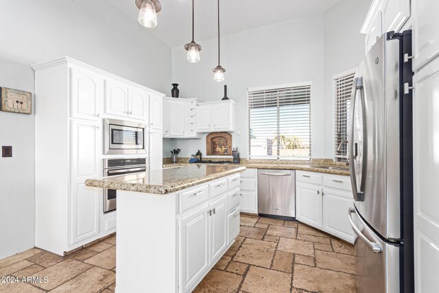 2731 W Desert Ranch Rd, Phoenix, AZ 85086 - kitchen featuring appliances with stainless steel finishes, stone tile flooring, a kitchen island, white cabinetry, and a high ceiling