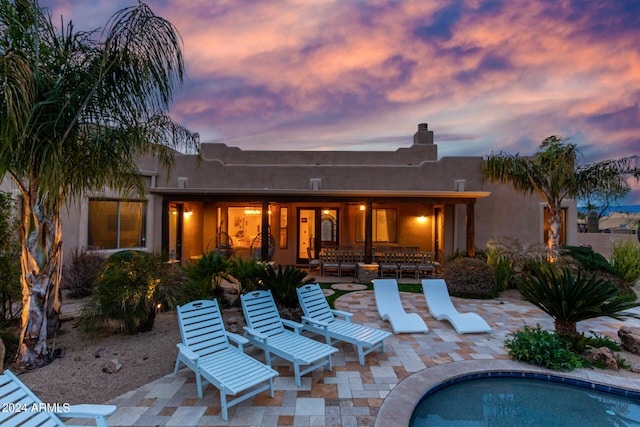 2731 W Desert Ranch Rd, Phoenix, AZ 85086 - back of property at dusk with a chimney, a patio, an outdoor pool, and stucco siding
