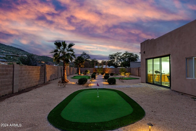 2731 W Desert Ranch Rd, Phoenix, AZ 85086 - yard at dusk with a putting green, a patio, and a fenced backyard