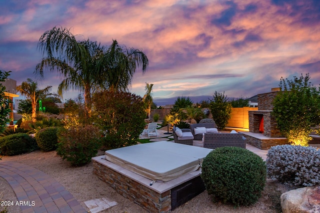 2731 W Desert Ranch Rd, Phoenix, AZ 85086 - yard at dusk with an outdoor stone fireplace, a patio area, and a covered hot tub