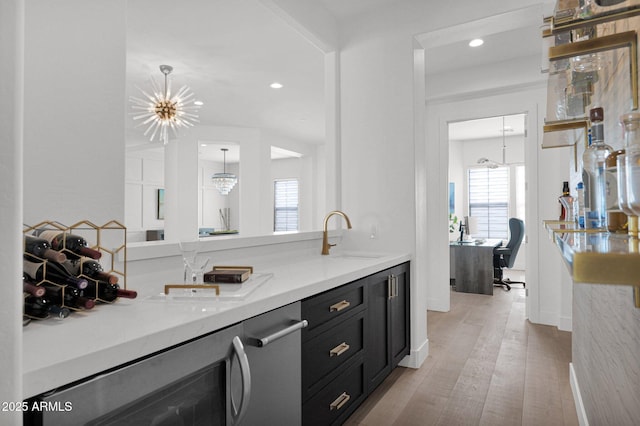 interior space featuring sink, an inviting chandelier, decorative light fixtures, beverage cooler, and light wood-type flooring