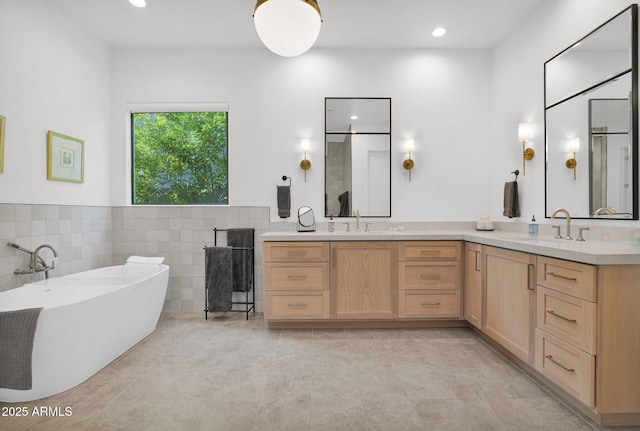 bathroom with tile patterned floors, vanity, tile walls, and a washtub