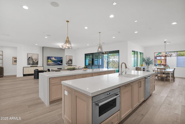 kitchen featuring a large island, light brown cabinetry, sink, and appliances with stainless steel finishes