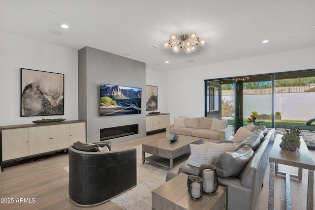 living room with a large fireplace, a chandelier, and light wood-type flooring