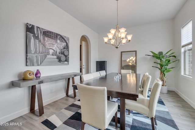 10886 N 137th St, Scottsdale, AZ 85259 - dining room with a chandelier, light wood-style flooring, arched walkways, and a wealth of natural light