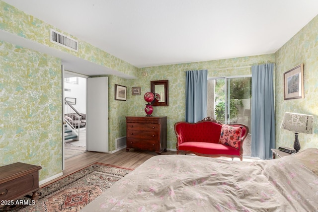 bedroom featuring wallpapered walls, wood finished floors, and visible vents