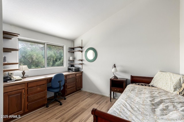 bedroom featuring light wood-type flooring, baseboards, and built in study area