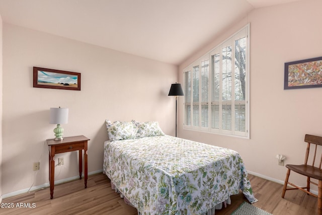 bedroom with baseboards, wood finished floors, and vaulted ceiling