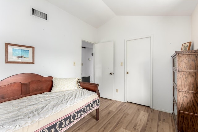 bedroom featuring vaulted ceiling, visible vents, and wood finished floors