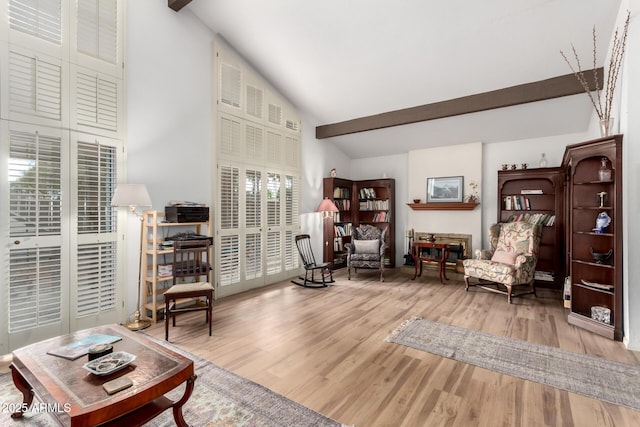 living area featuring beamed ceiling, high vaulted ceiling, and wood finished floors