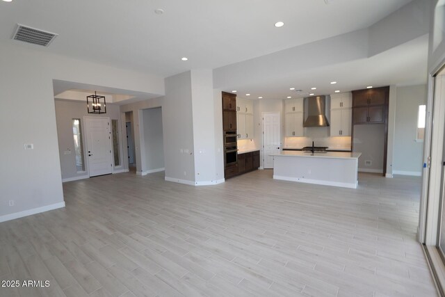20209 W San Miguel Ave, Litchfield Park, AZ 85340 - unfurnished living room featuring a chandelier, baseboards, recessed lighting, light wood finished floors, and a sink