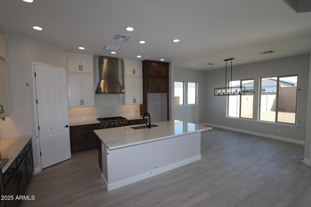 20209 W San Miguel Ave, Litchfield Park, AZ 85340 - kitchen with wall chimney range hood, a sink, light wood-style floors, baseboards, and recessed lighting