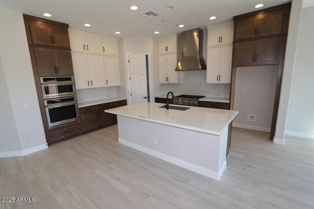 20209 W San Miguel Ave, Litchfield Park, AZ 85340 - kitchen featuring wall chimney range hood, a sink, light wood-type flooring, baseboards, and recessed lighting