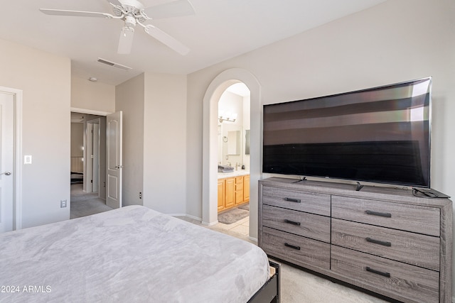 bedroom with ceiling fan, light carpet, and ensuite bath