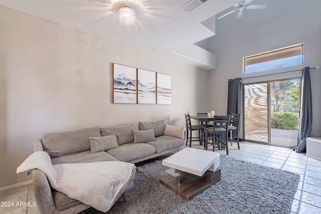 tiled living room featuring ceiling fan and a high ceiling