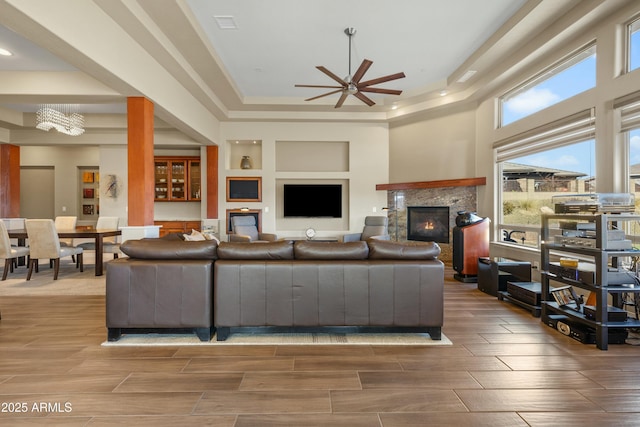 living room with ceiling fan with notable chandelier and a tray ceiling