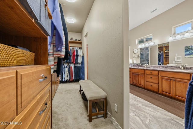 walk in closet with light carpet and sink