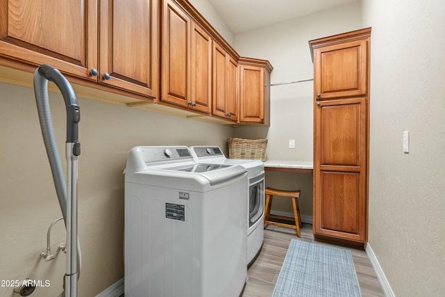 clothes washing area featuring cabinets, separate washer and dryer, and light hardwood / wood-style flooring