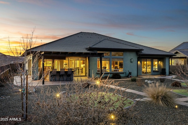 back house at dusk with a patio