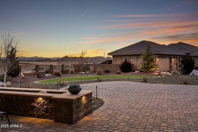 patio terrace at dusk with a garage and a mountain view