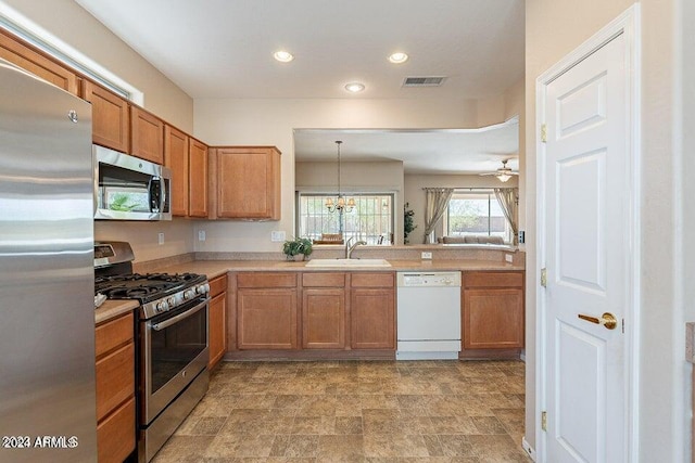 kitchen with ceiling fan with notable chandelier, sink, stainless steel appliances, and decorative light fixtures