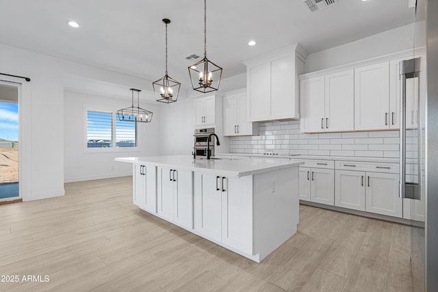 2083 W Lincoln Ct, San Tan Valley, AZ 85144 - kitchen with a chandelier, light countertops, white cabinetry, tasteful backsplash, and a center island with sink