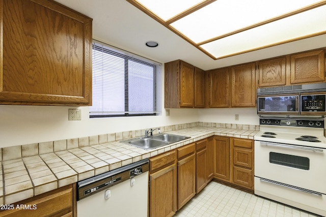 kitchen featuring brown cabinetry, white appliances, a sink, and tile countertops