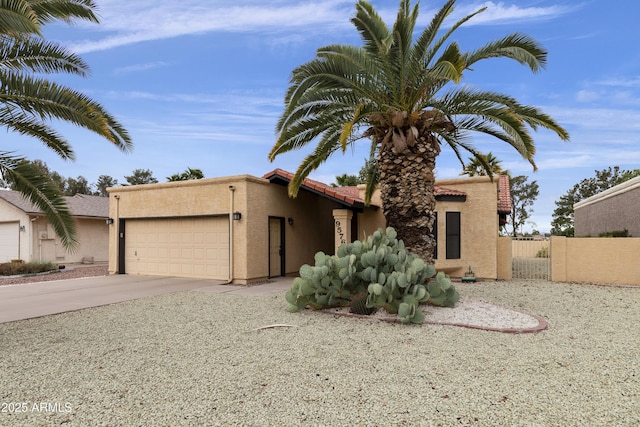 view of front of home with a garage, concrete driveway, a tiled roof, fence, and stucco siding