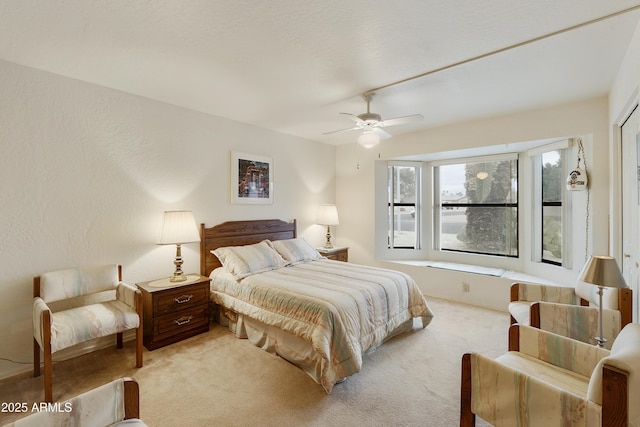 bedroom featuring a textured wall, light carpet, and ceiling fan