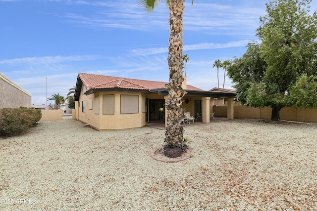 rear view of house featuring a patio area, fence, a tile roof, and stucco siding