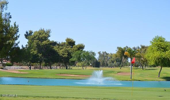 view of home's community with view of golf course, a water view, and a lawn