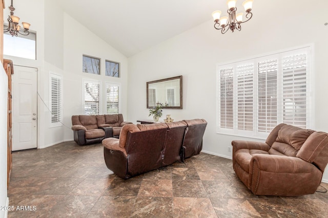living area with baseboards, high vaulted ceiling, stone finish floor, and an inviting chandelier