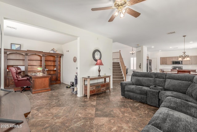 living room with stairway, visible vents, and ceiling fan with notable chandelier