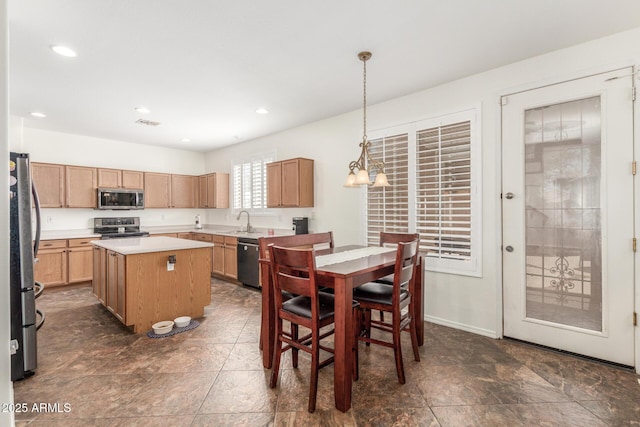 kitchen featuring hanging light fixtures, a sink, light countertops, stainless steel appliances, and a kitchen island