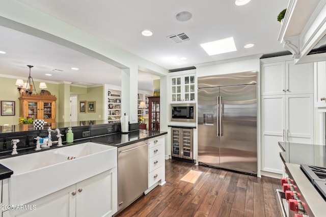 4710 N 33rd Pl, Phoenix, AZ 85018 - kitchen with built in appliances, beverage cooler, white cabinets, ornamental molding, and dark wood-style flooring