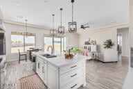 kitchen featuring white cabinetry, a center island with sink, a wealth of natural light, and hanging light fixtures