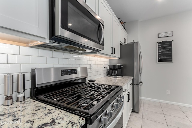 kitchen featuring backsplash, white cabinetry, light stone countertops, appliances with stainless steel finishes, and light tile patterned floors