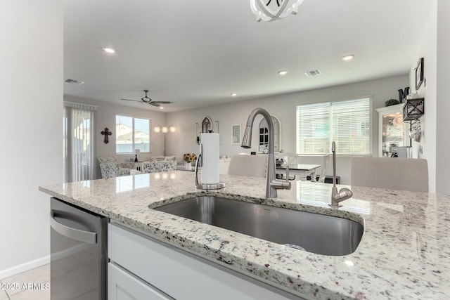 kitchen featuring ceiling fan, dishwasher, sink, light tile patterned floors, and light stone counters