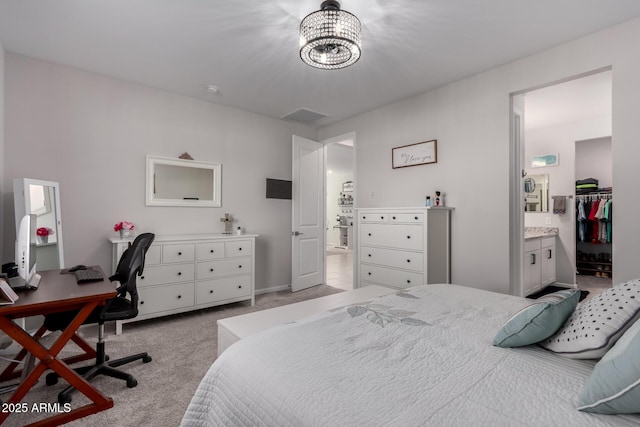 bedroom featuring a walk in closet, a closet, a chandelier, light colored carpet, and ensuite bathroom