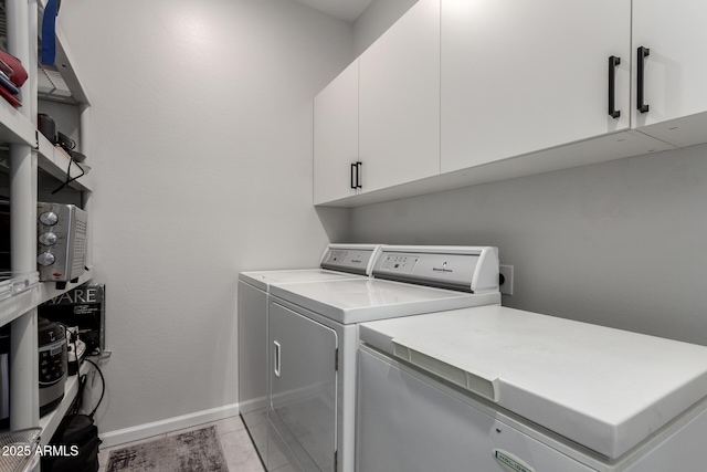 laundry area with light tile patterned floors, cabinets, and washer and dryer