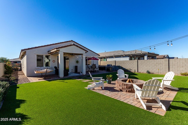 rear view of house featuring a patio area, an outdoor fire pit, and a yard