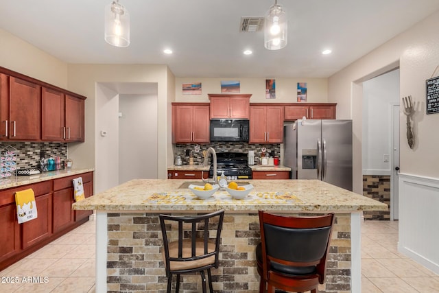 18669 W Vista Norte St, Goodyear, AZ 85338 - kitchen featuring black appliances, light tile patterned floors, decorative backsplash, decorative light fixtures, and light stone countertops