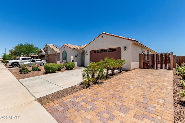 18669 W Vista Norte St, Goodyear, AZ 85338 - mediterranean / spanish house featuring concrete driveway, stucco siding, an attached garage, a gate, and a tiled roof