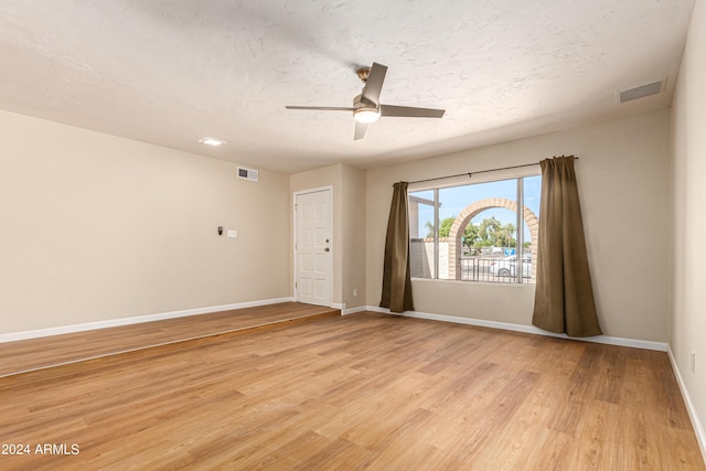 spare room featuring ceiling fan, light hardwood / wood-style flooring, and a textured ceiling