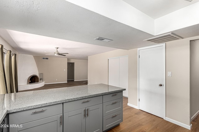 kitchen featuring gray cabinets, light stone countertops, and light hardwood / wood-style floors