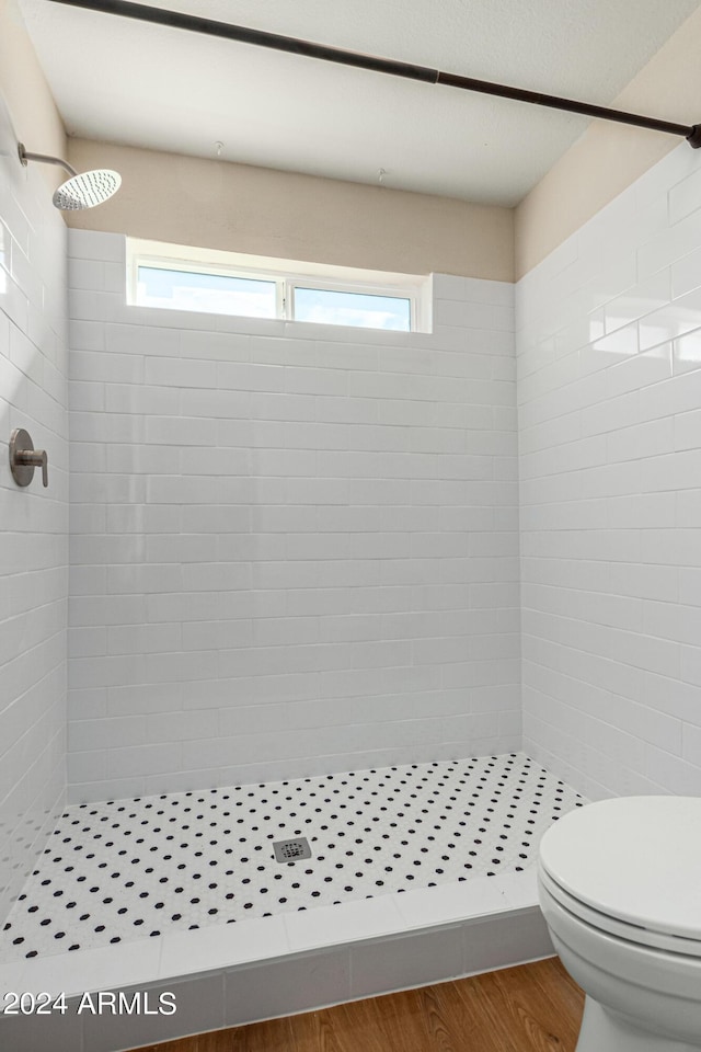 bathroom featuring hardwood / wood-style floors, a tile shower, and toilet