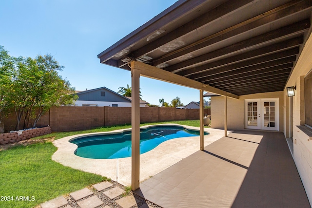 view of pool with french doors, a patio, and a lawn