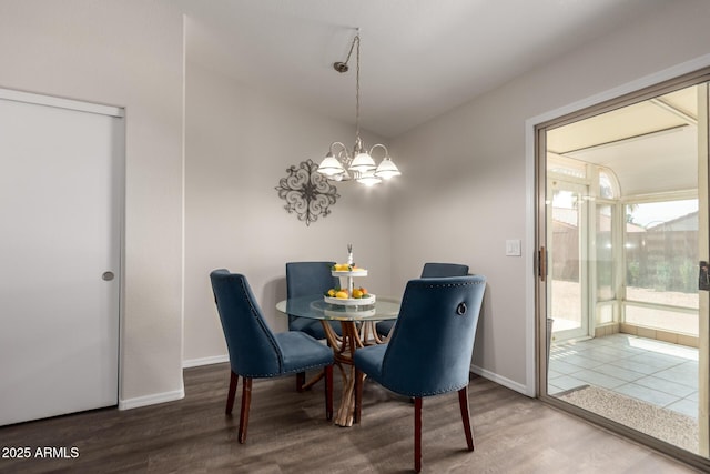 dining space with baseboards, wood finished floors, and a notable chandelier