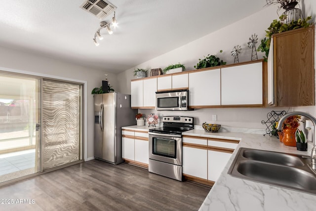 kitchen with a sink, stainless steel appliances, white cabinetry, and dark wood-type flooring